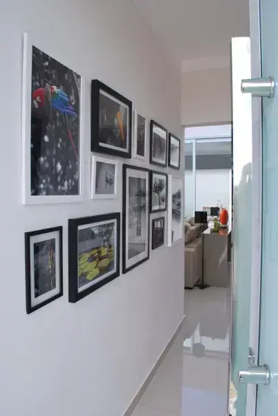 Parede de quadros no corredor com molduras em preto e branco (foto: Projética Design e Arquitetura)