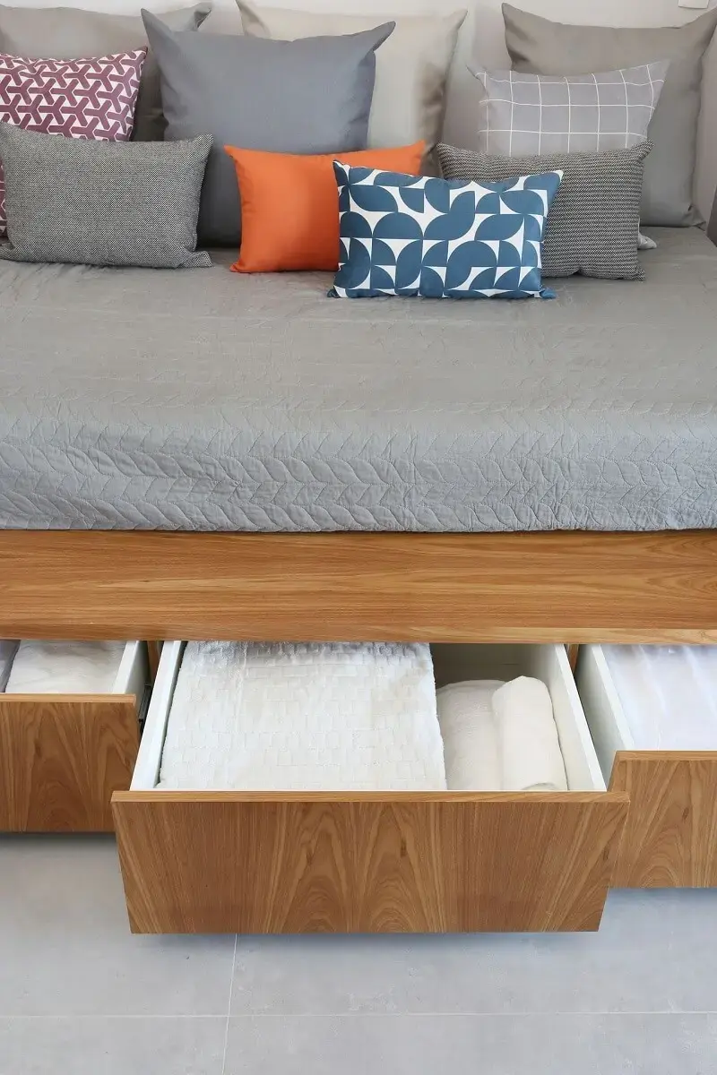 Aproveite a estrutura da cama multifuncional para organizar roupas de cama, mesa e banho dentre outros acessórios. Fonte: ACF Arquitetura