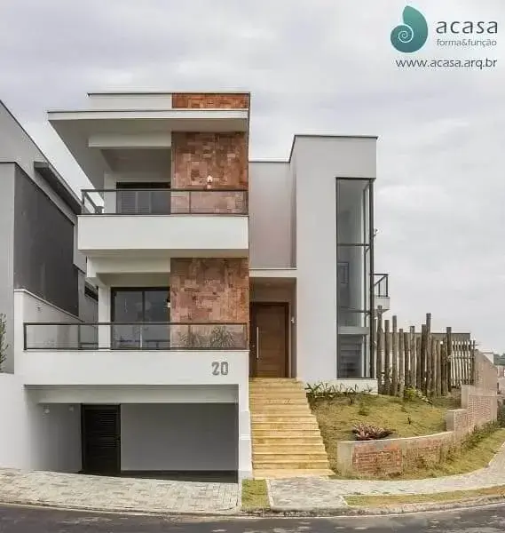 Garagem subterrânea em casa com fachada branca e tijolinhos (foto: ACASA forma&função)